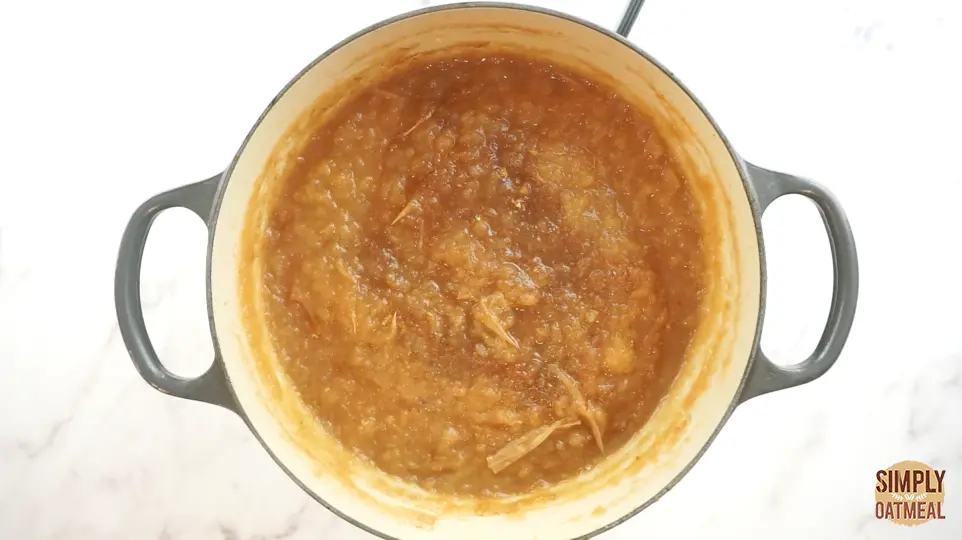 Apple butter being cooked in large dutch oven. The puree is beginning to turn a rich caramel color and complex flavors are developing.