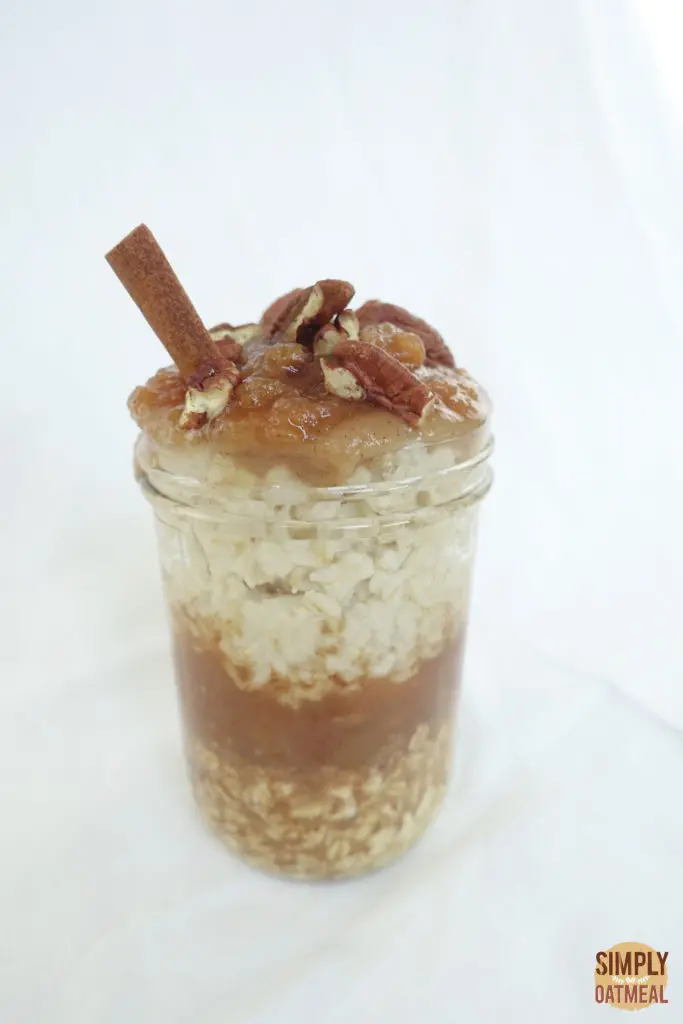 One serving of apple cider overnight oats in a tall glass container.