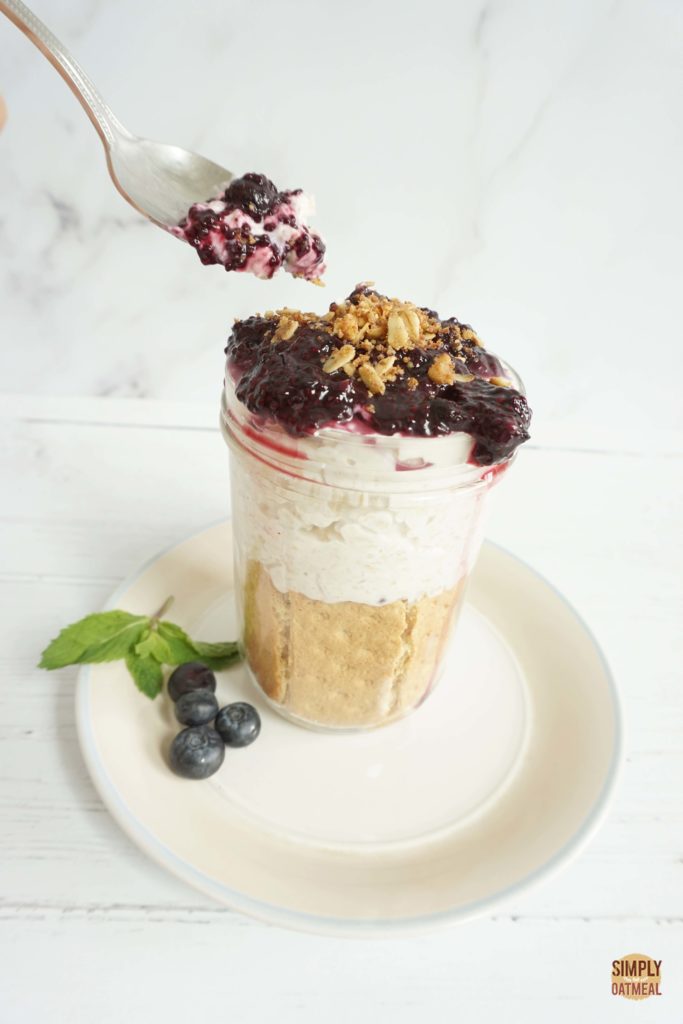 Spoonful of blueberry cheesecake overnight oats taken from a glass jar.