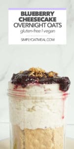 A tall glass jar filled with one serving of blueberry cheesecake overnight oats. The oatmeal is layered with crunchy graham crackers as a cheesecake crust.