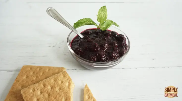 Small glass bowl with blueberry chia jam with graham crackers on the side