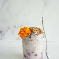 Blueberry honey overnight oats in a jar with a spoon propped against the side.
