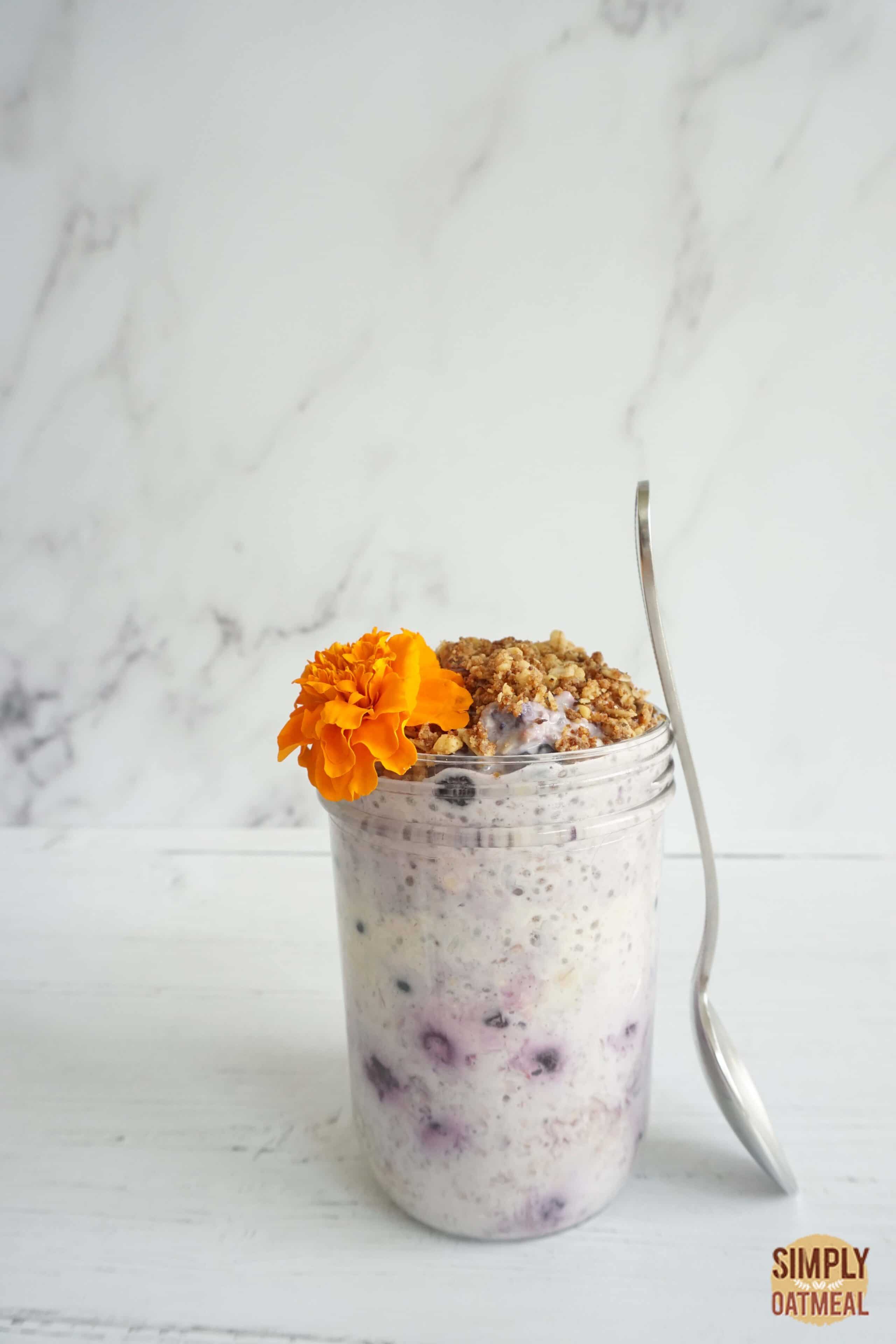 Blueberry honey overnight oats in a jar with a spoon propped against the side.