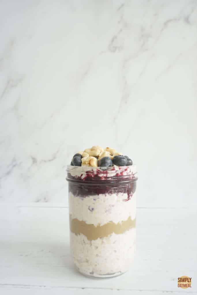 Blueberry peanut butter overnight oats layered inside a mason jar.