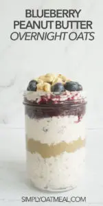 Layers of creamy overnight oats, peanut butter and blueberry jam inside a glass container.