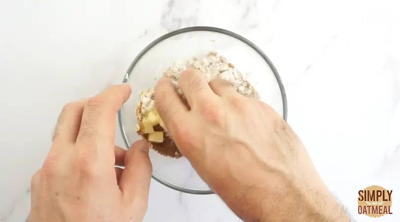 Use your fingertips to work the butter into the oatmeal crumble topping. The cold butter should be worked into pea-sized crumbles inside the mixture.