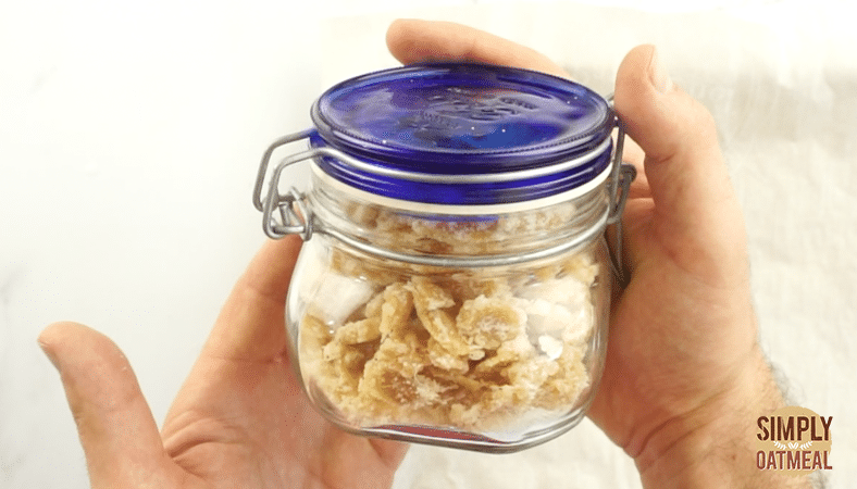 Homemade candied ginger being stored in a small glass jar