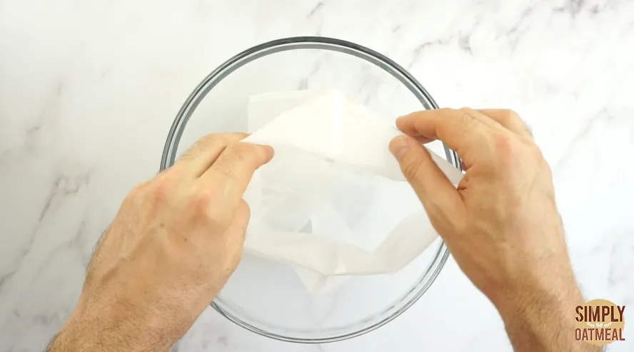 Nut milk bag placed inside a large glass bowl