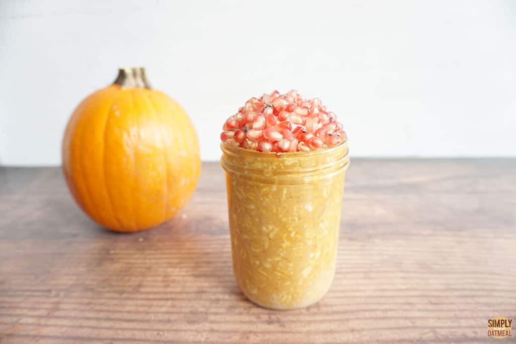 one serving of pumpkin puree overnight oats in a glass jar next to a whole sugar pie pumpkin