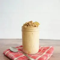 Pumpkin spice overnight oats in a glass container with a spoon on the side