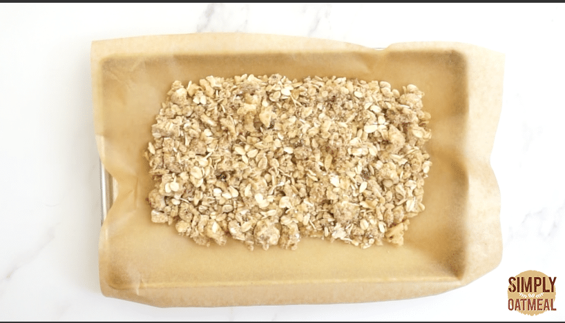 The raw oatmeal crumble topping is on a baking sheet and is prepared to be placed into the oven.