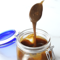 spoonful of caramel sauce from glass jar.