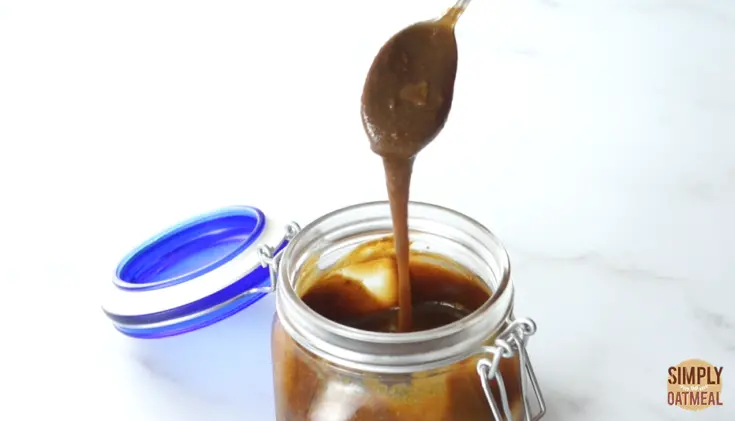 spoonful of caramel sauce from glass jar.