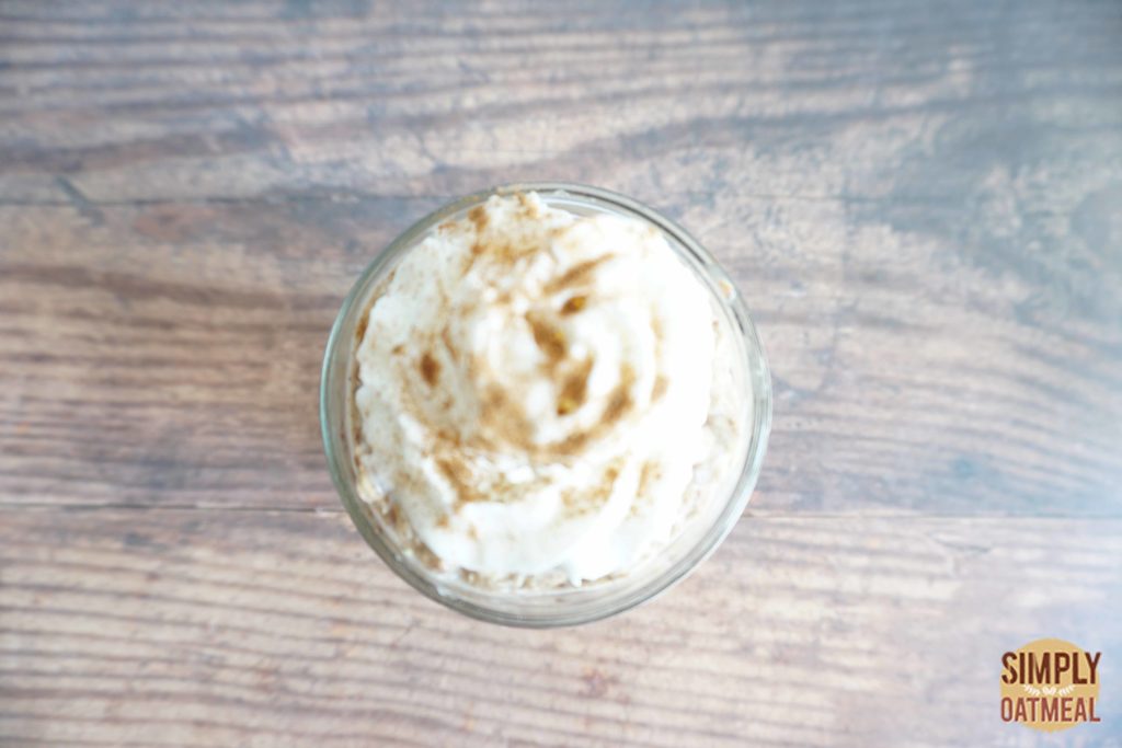 Banana bread overnight oats topped with fresh whipped cream sprinkled with powdered cinnamon and brown sugar