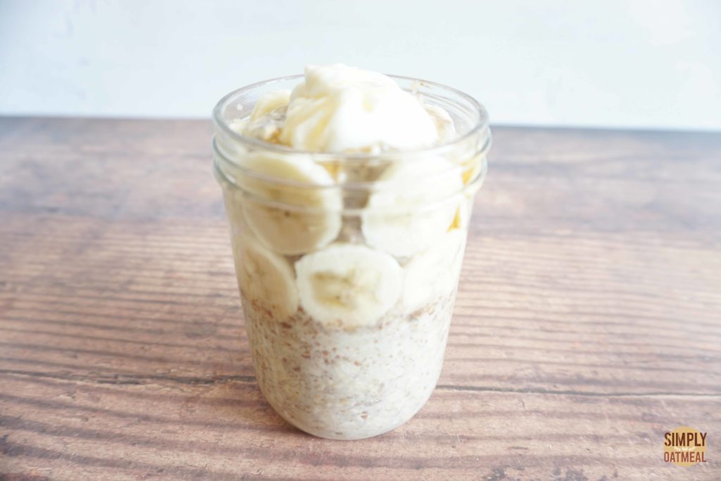 Banana honey overnight oats in a glass jar with slices of banana layered around the sides.