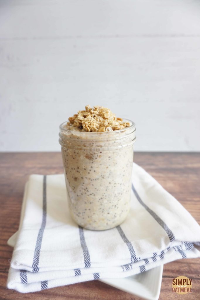 Banana yogurt overnight oats served in a glass container that is placed on top of a white kitchen towel