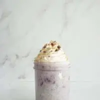 Mason jar filled with blueberry chia overnight oats and topped with whipped cream, cocoa nibs and a sprinkle of cinnamon.