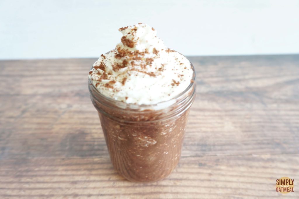 Serving of mocha banana overnight oats topped with latte foam and cinnamon powder.