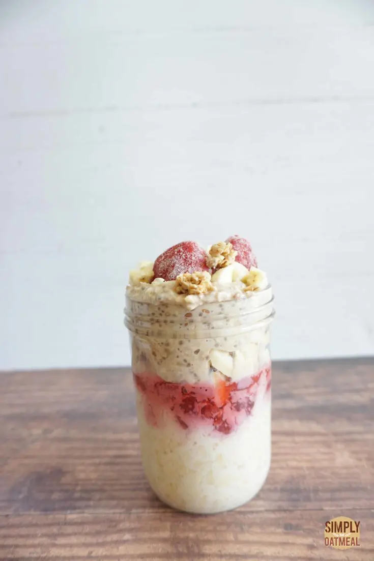 Serving of strawberry banana overnight oats in a mason jar. No cook oats with a layer of strawberry jam in between