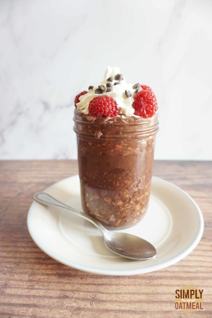 Raspberry chocolate overnight oats in a meal prep container with a spoon laying aside