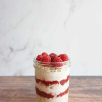 Layers of raspberry jam and overnight oats in a mason jar.