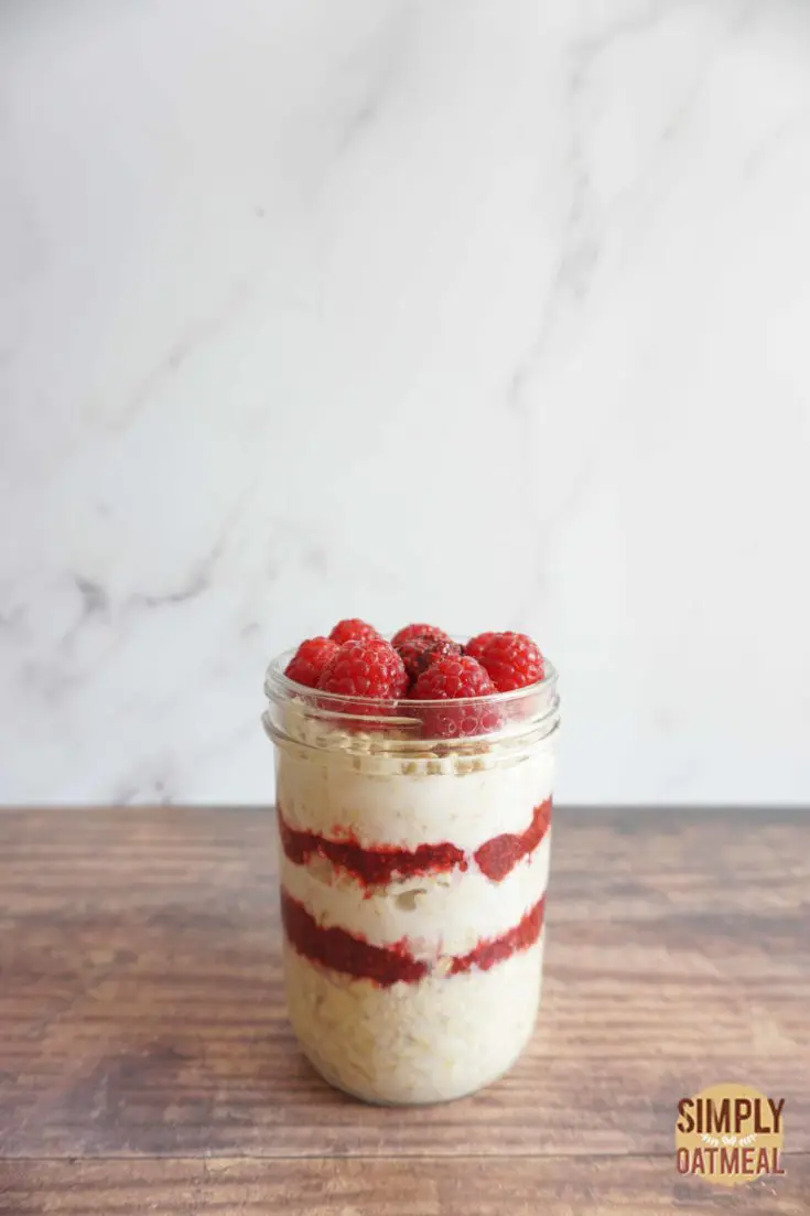 Layers of raspberry jam and overnight oats in a mason jar.