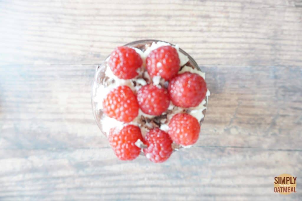 Raspberry mocha overnight oats garnished with whipped cream and fresh raspberries