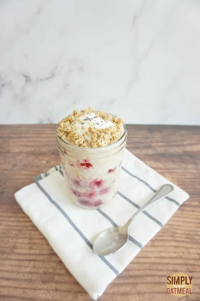 Meal prep container filled with raspberry yogurt overnight oats. A spoon is laying along side the no cook oatmeal.