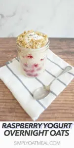 Raspberry yogurt overnight oats served in a glass container with a spoon on the side.