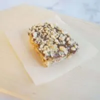 A single no bake chocolate peanut butter fudge oatmeal bar on a piece of parchment paper