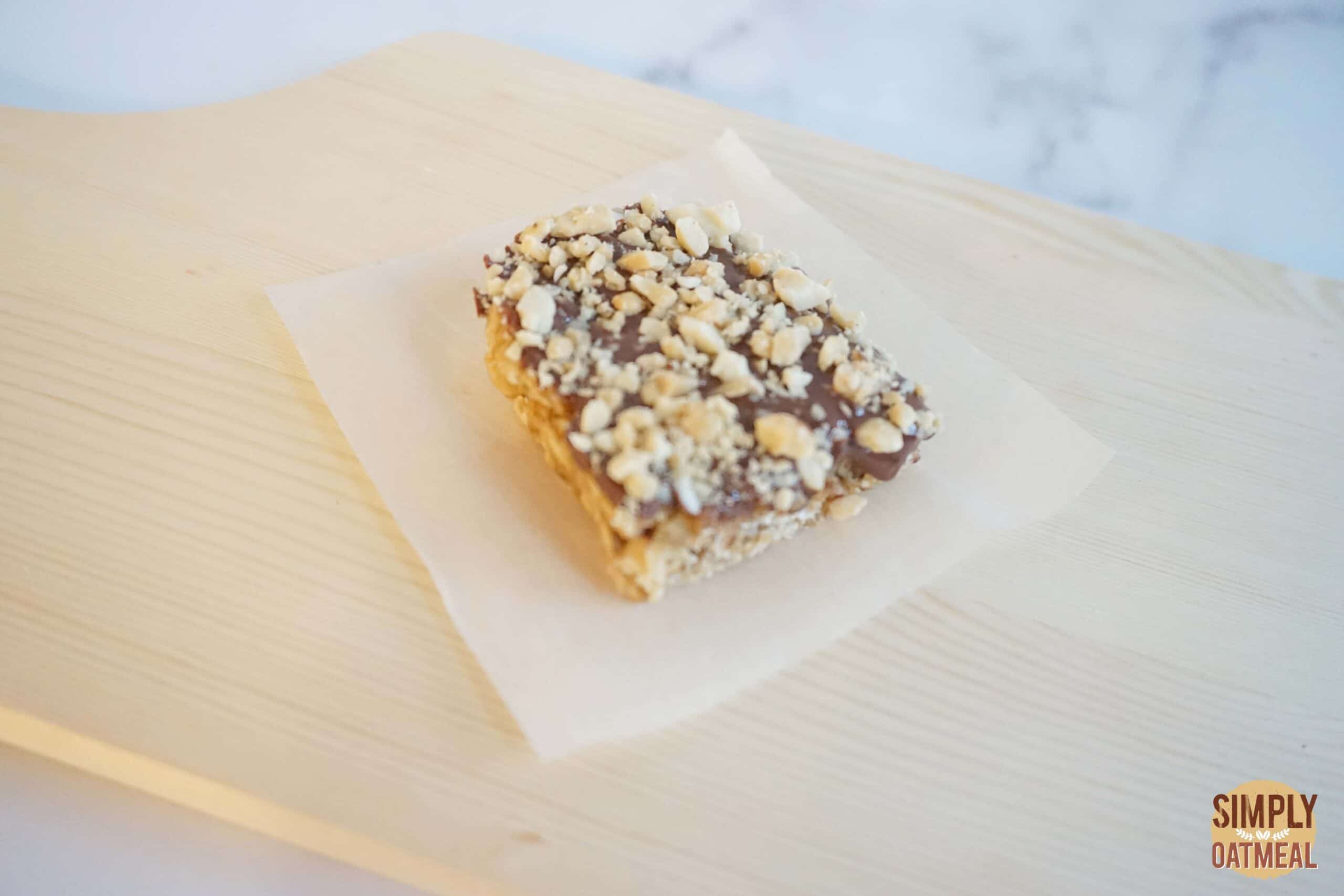 A single no bake chocolate peanut butter fudge oatmeal bar on a piece of parchment paper