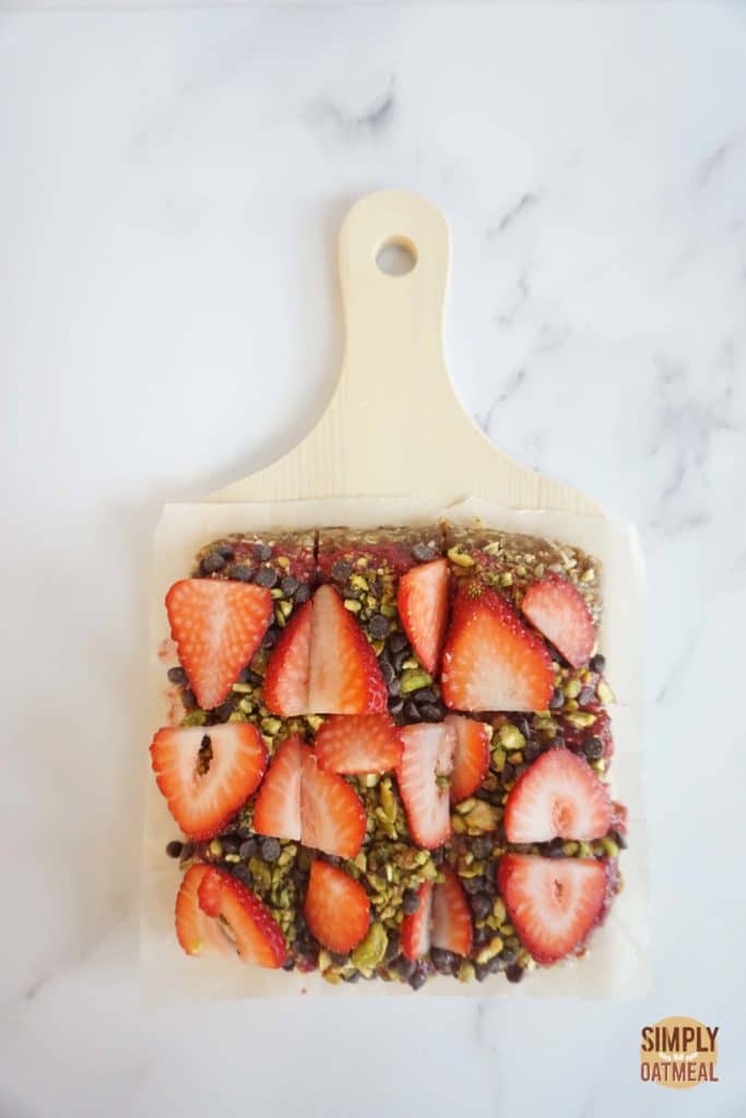 No bake strawberry oatmeal bars cut into squares and served on a wooden cutting board