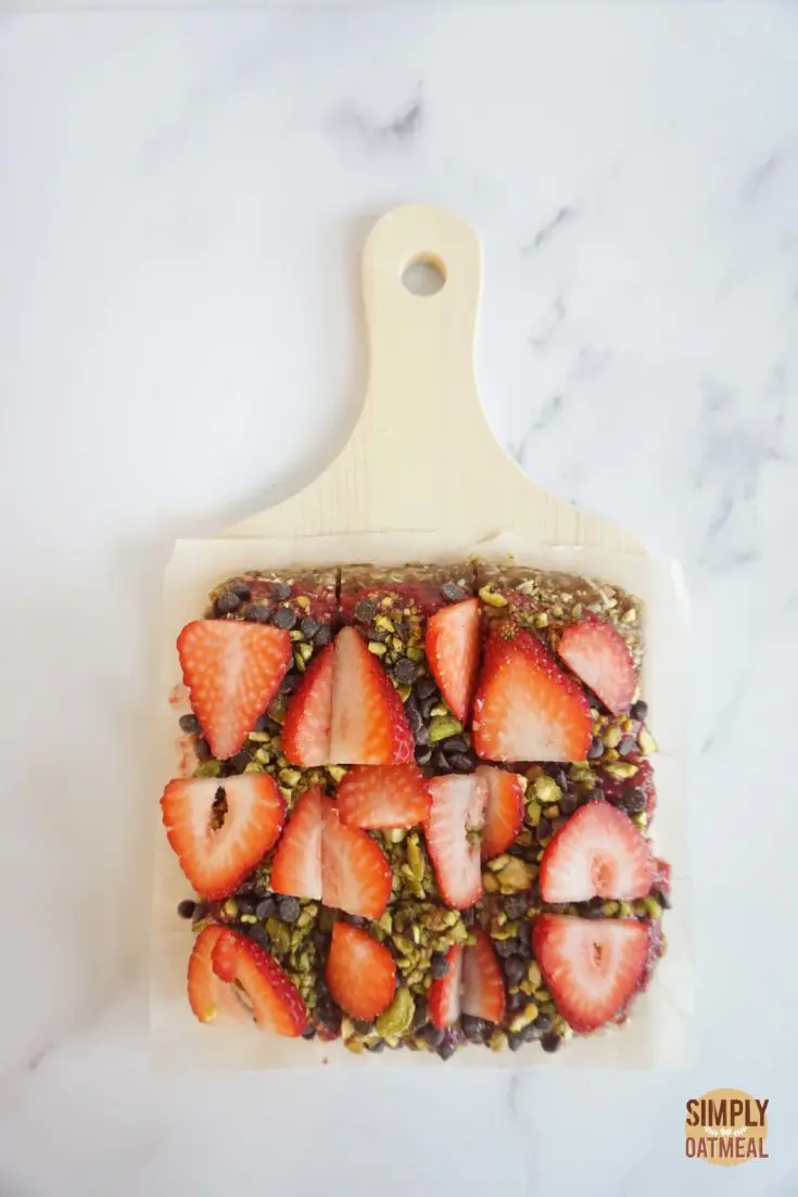 No bake strawberry oatmeal bars cut into squares and served on a wooden cutting board