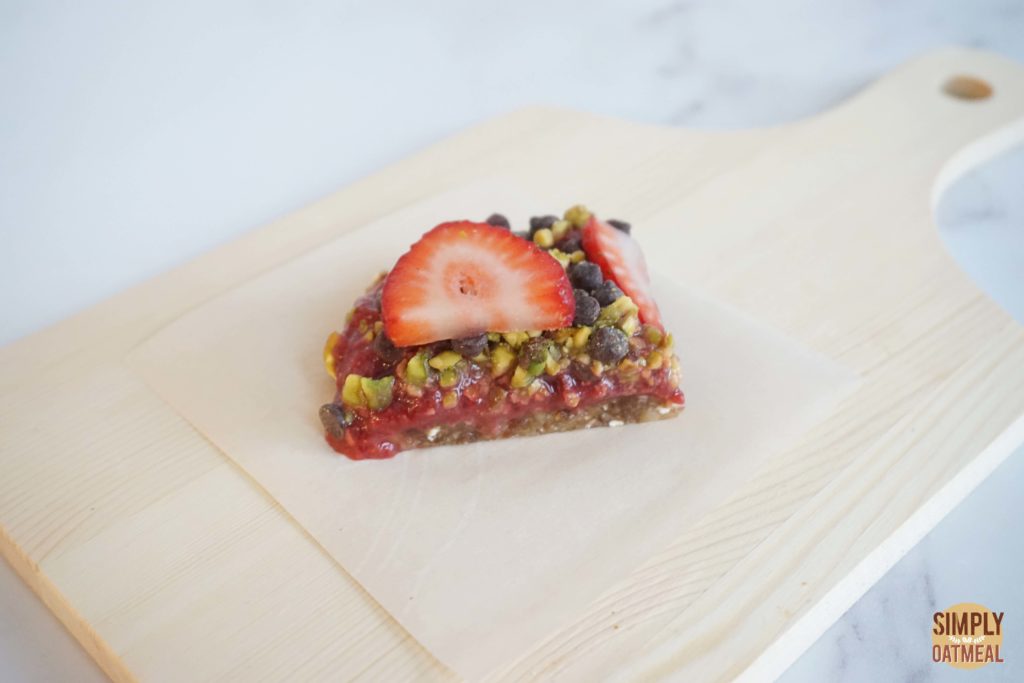 One piece of no bake strawberry oatmeal bar on a wood plate
