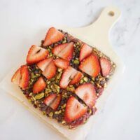 No bake strawberry oatmeal bars topped with sliced strawberries, pistachios and mini chocolate chips