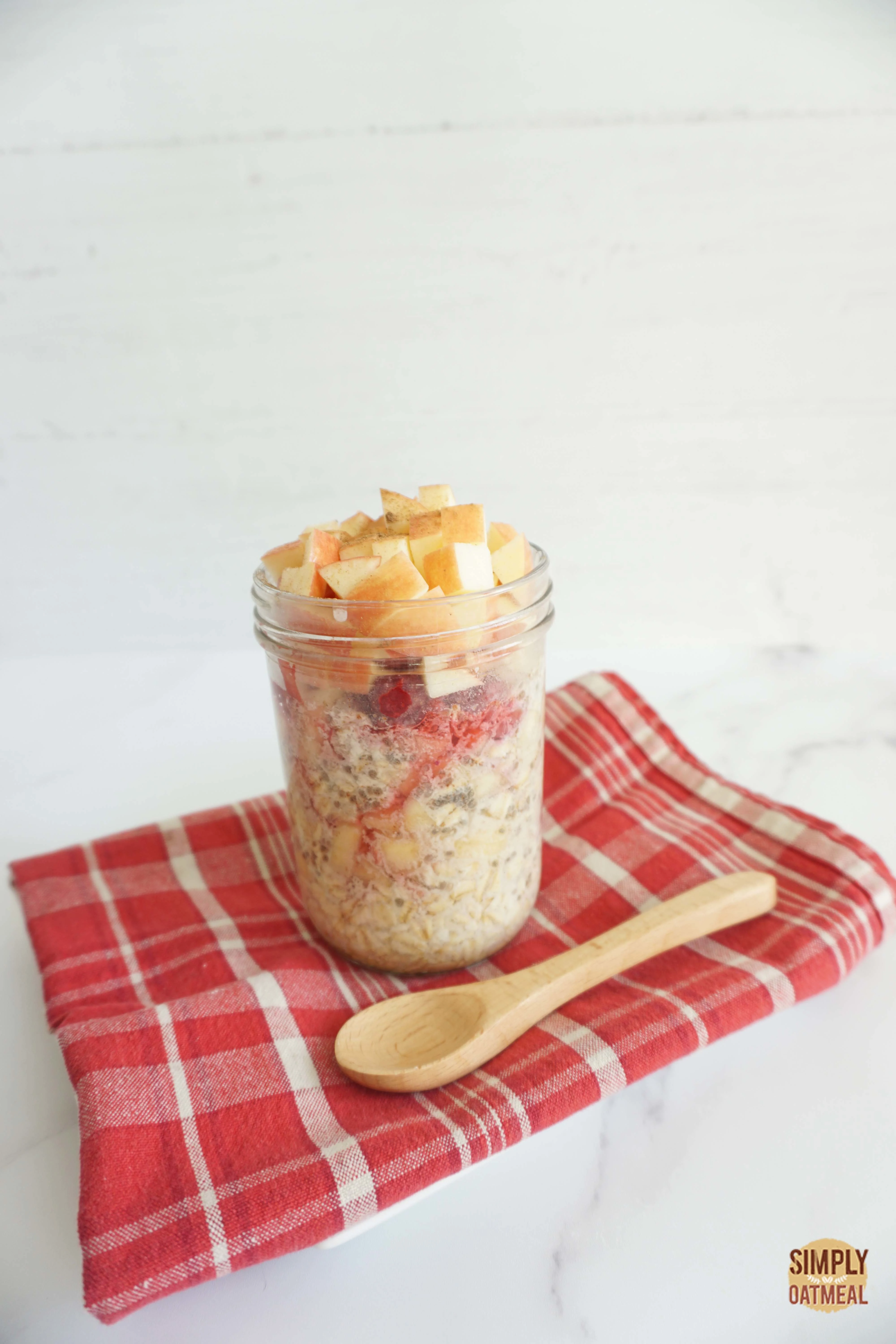 Apple raspberry overnight oats served in a mason jar with a spoon on the side