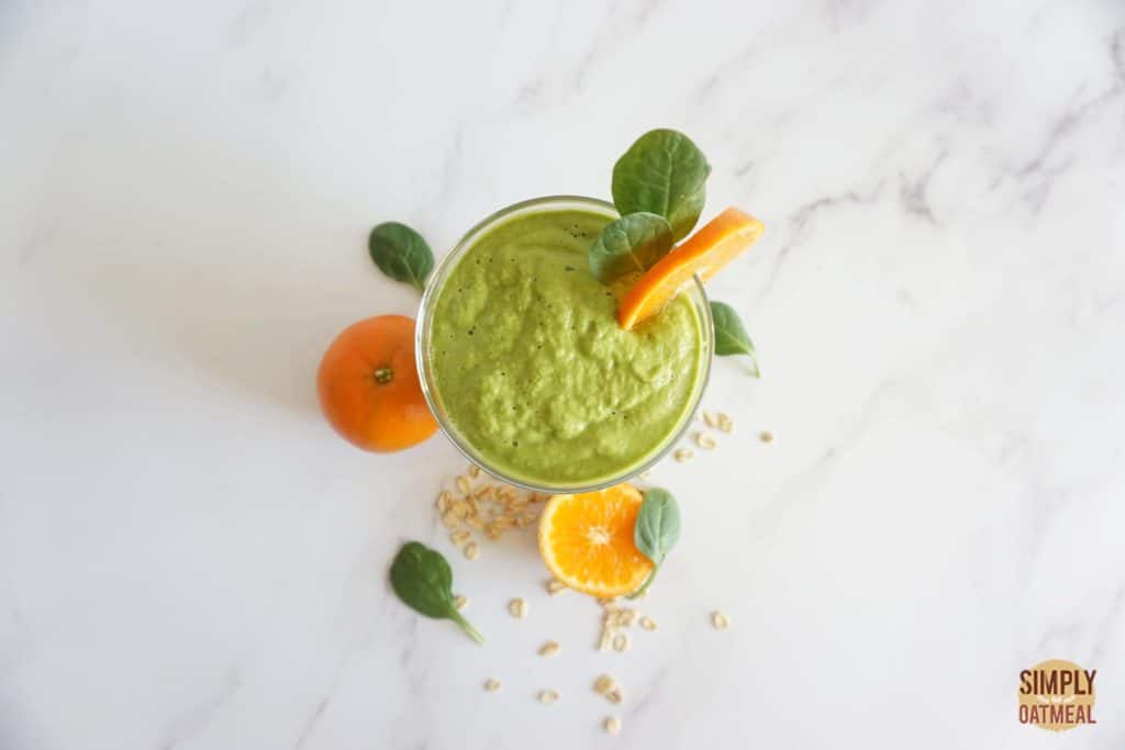 Avocado dreamsicle oatmeal smoothie garnished with sliced orange and spinach leaves.