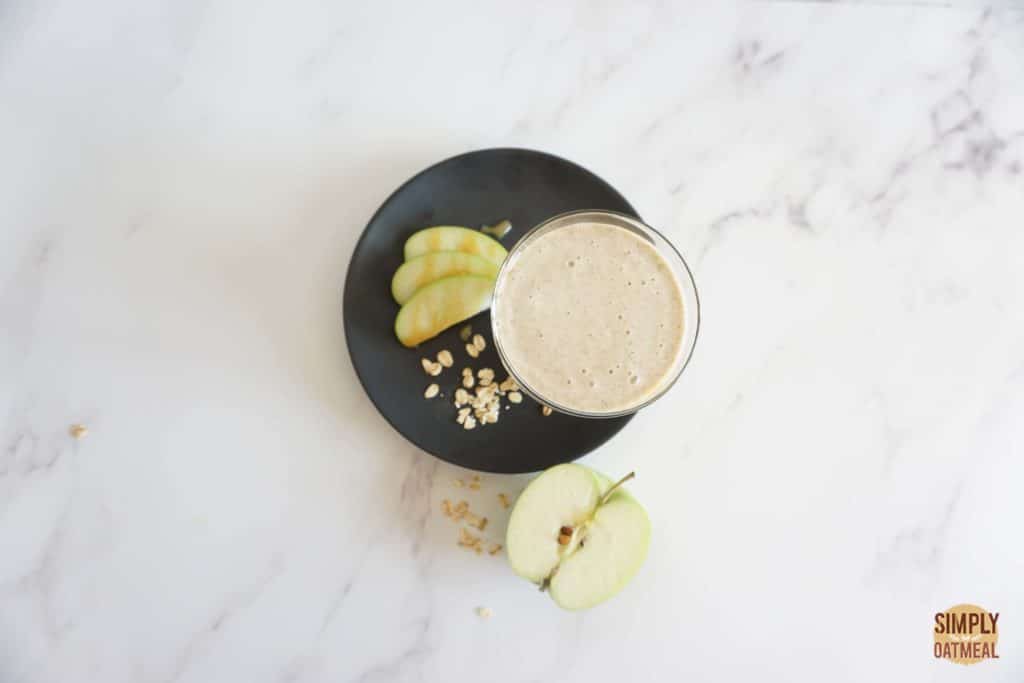 Caramel apple oatmeal smoothie with caramel sauce and sliced green apple on the side