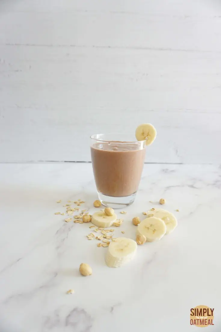 Single serving of chocolate peanut butter banana oatmeal smoothie in a glass cup