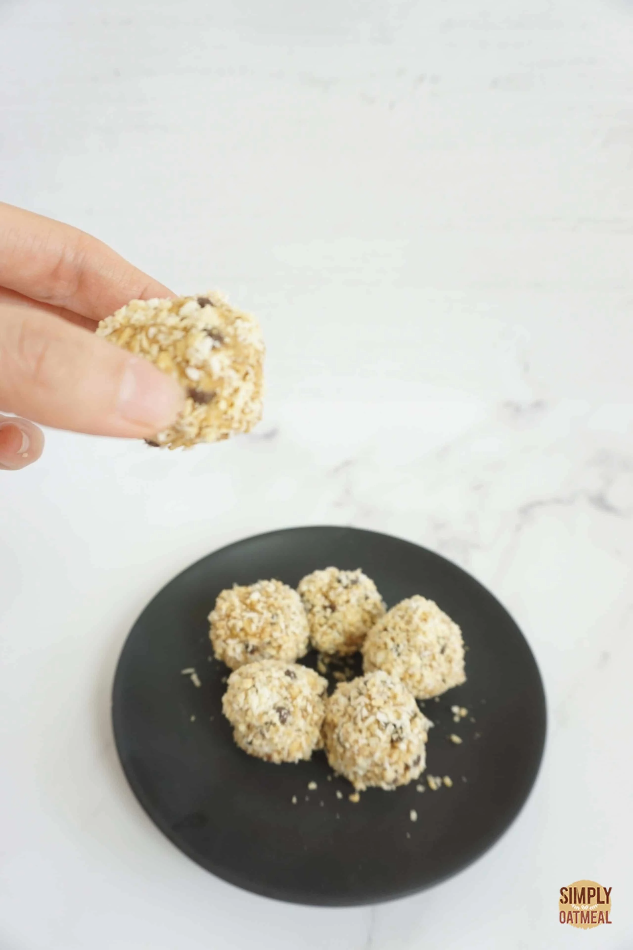 Fingers holding one no bake peanut butter oatmeal ball