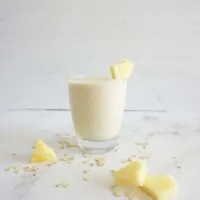 Single serving of piña colada oatmeal smoothie in a glass cup.