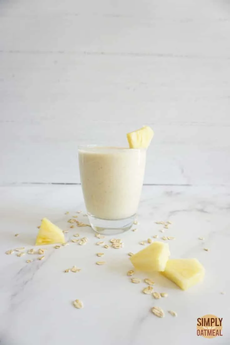 Single serving of piña colada oatmeal smoothie in a glass cup.