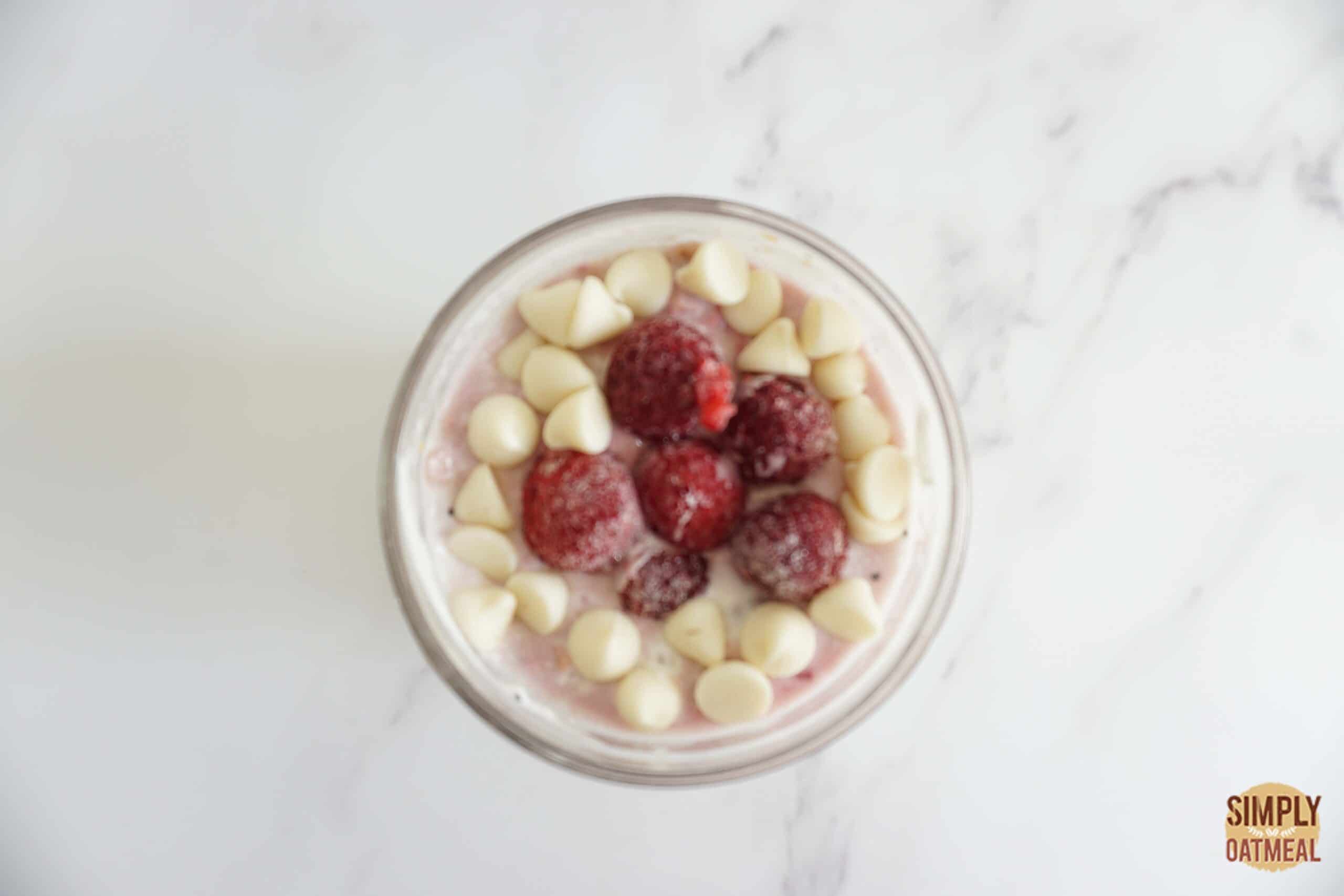 Raspberry white chocolate overnight oats topped with fresh raspberries and white chocolate chips.