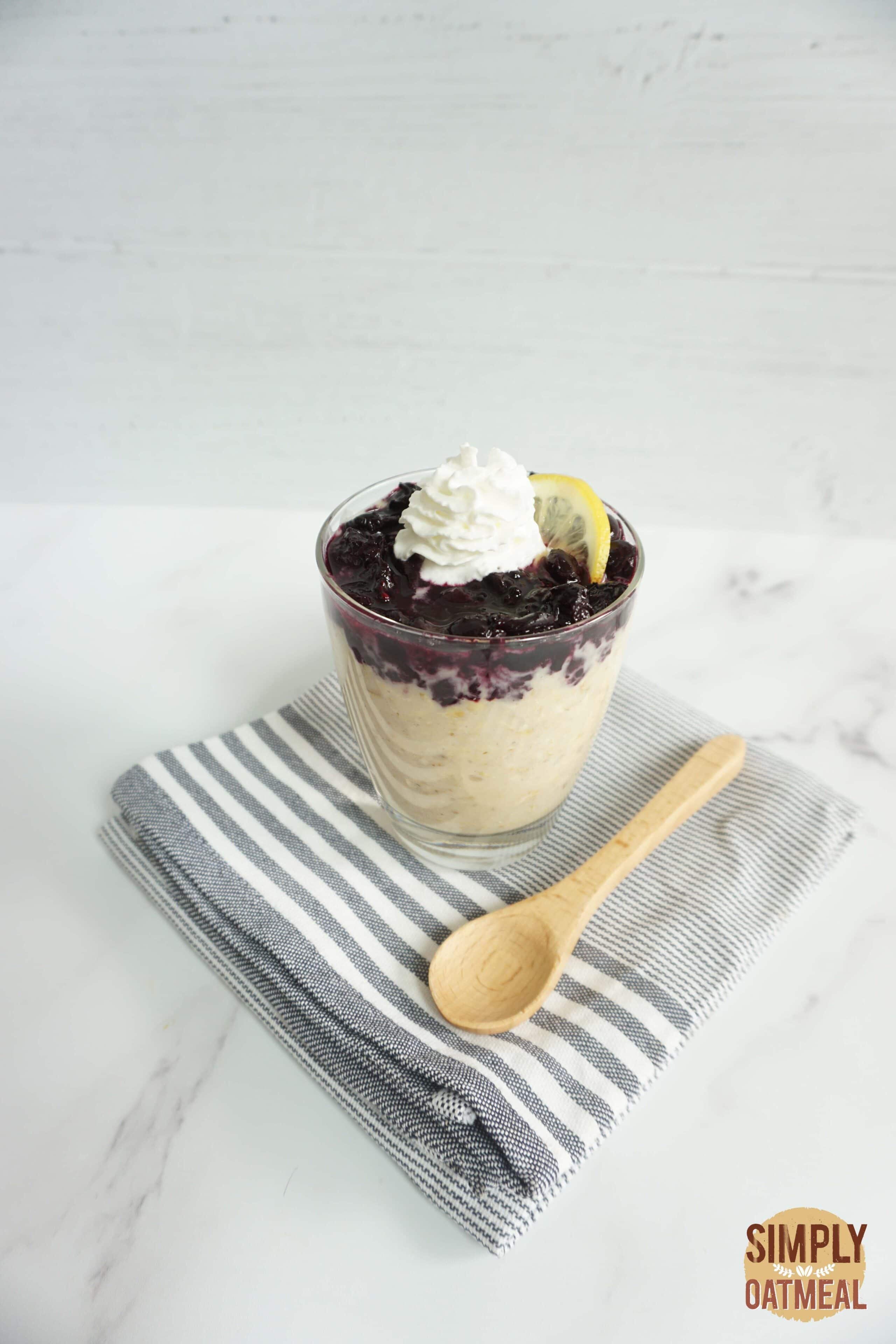 Blueberry lemonade overnight oats served in a glass cup with a wooden spoon on the side