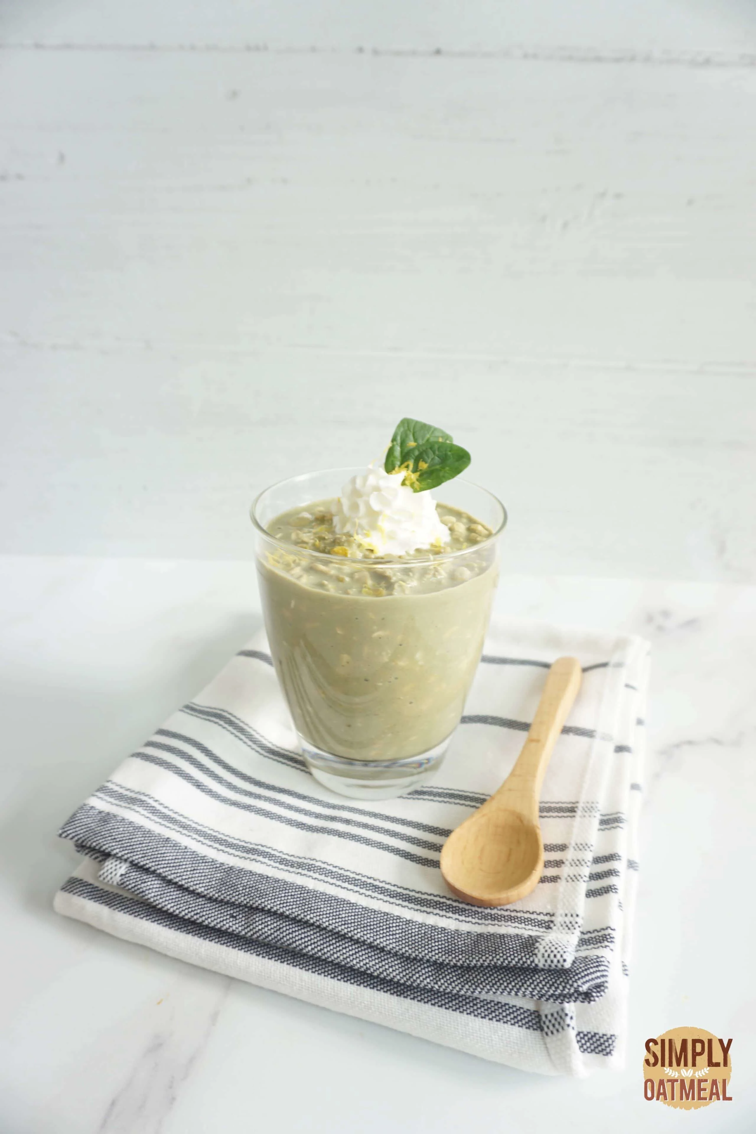 Green tea lemonade overnight oats served in a glass cup with sliced lemon and macha powder