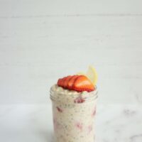 Single serving of lemon strawberry overnight oats in a mason jar with sliced strawberries on top