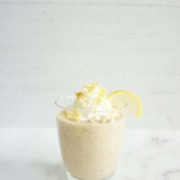 Single portion of lemonade overnight oats served in a glass cup garnished with lemon zest