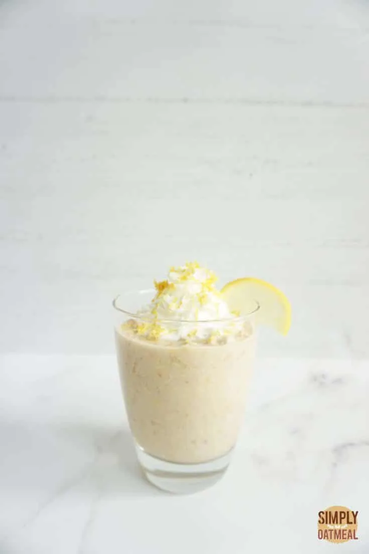 Single portion of lemonade overnight oats served in a glass cup garnished with lemon zest