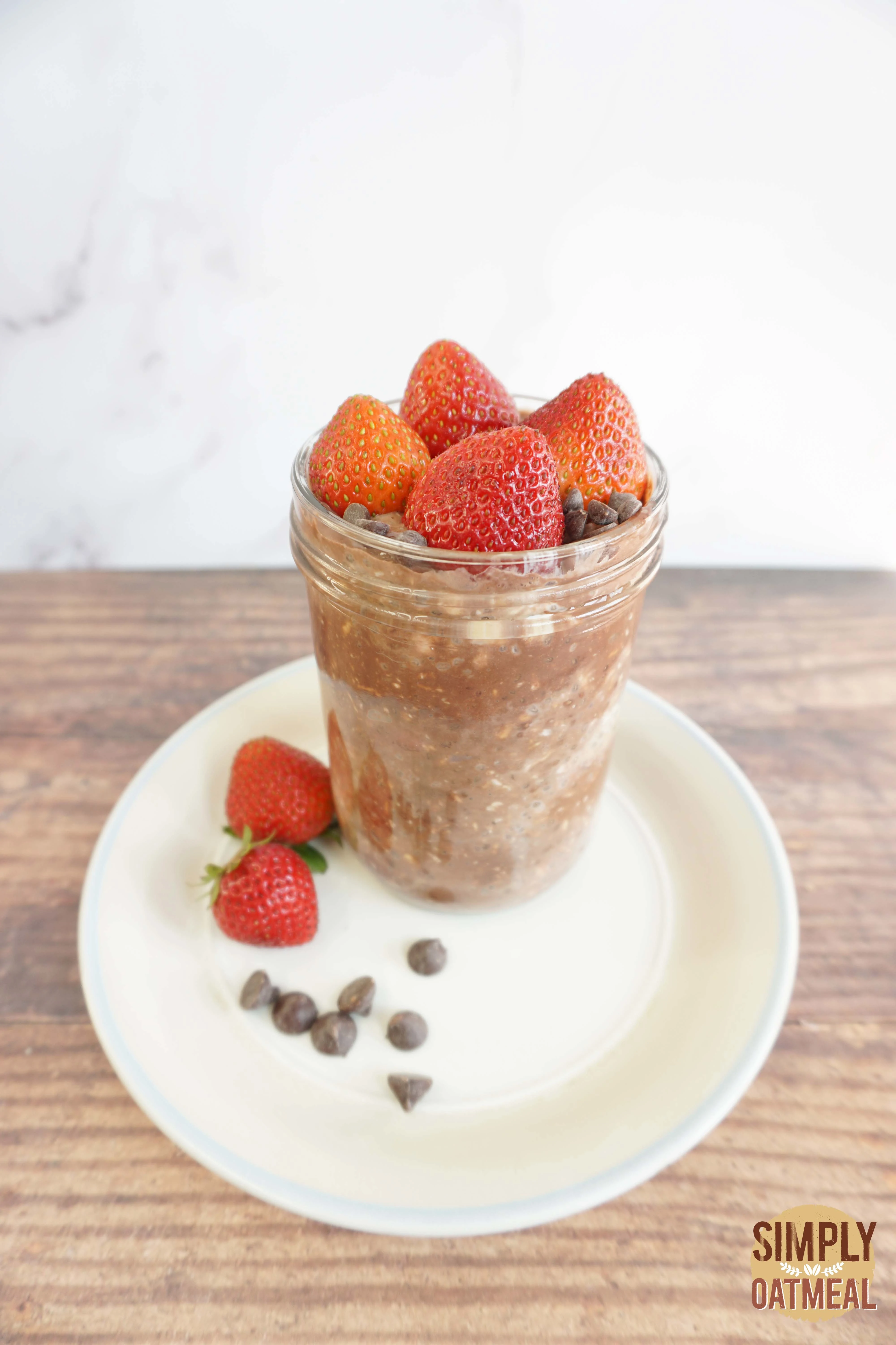 Strawberry chocolate overnight oats in a mason jar garnished with sliced strawberries and sprinkled with cocoa powder