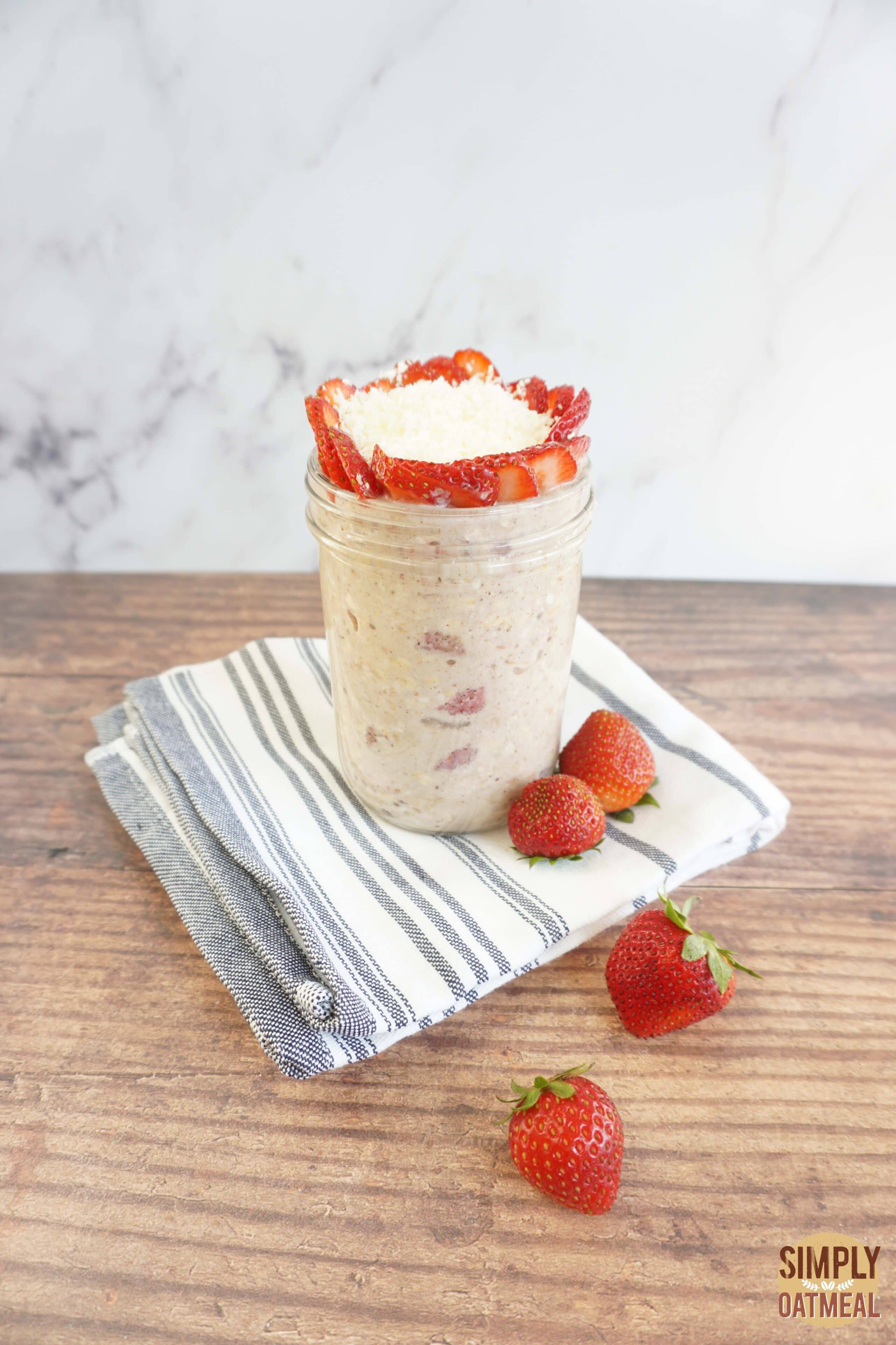 Strawberry coconut overnight oats in a mason jar with wild strawberries and shredded coconut on top.